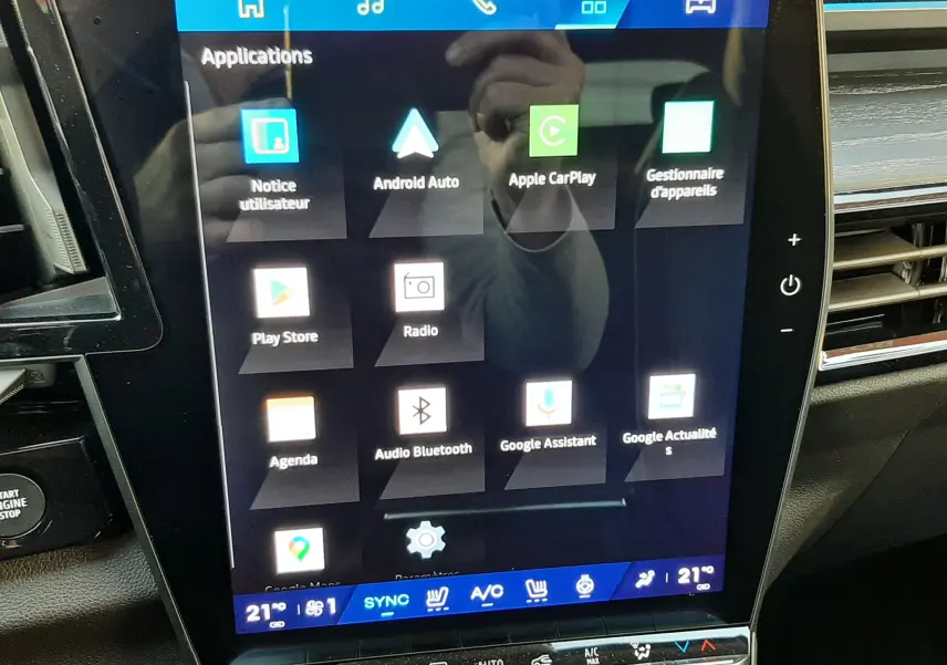 Écran tactile central du Renault Austral E-Tech 2025 affichant les applications connectées, avec tableau de bord noir en arrière-plan.
