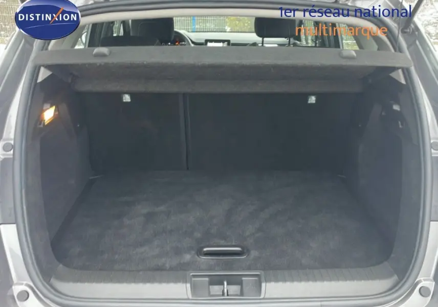 Coffre ouvert vu de l'arrière du Renault Captur gris Cassiopée Métal, espace de chargement vide et propre.