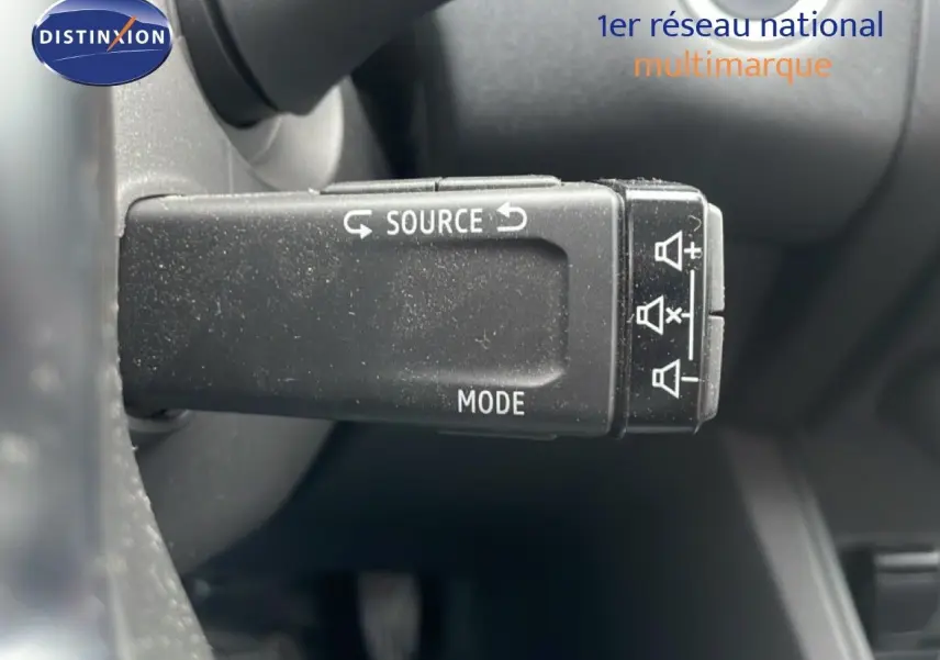 Gros plan sur la commande au volant du Renault Captur gris cassiopée métal, mettant en valeur les boutons source et mode.