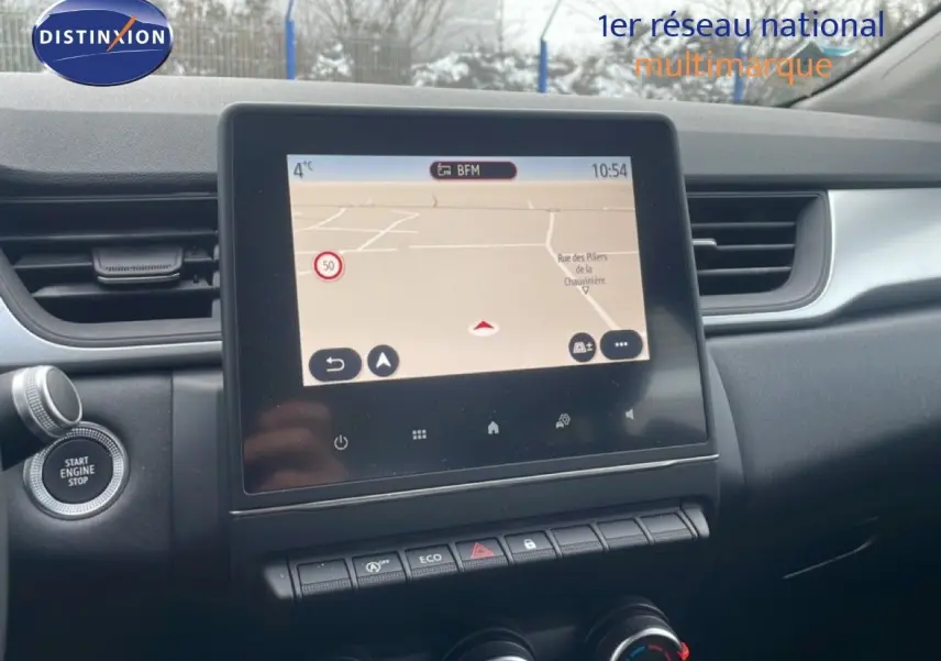 Vue intérieure centrée sur l'écran tactile du tableau de bord du Renault Captur gris Cassiopée, avec commandes climatisation visibles.