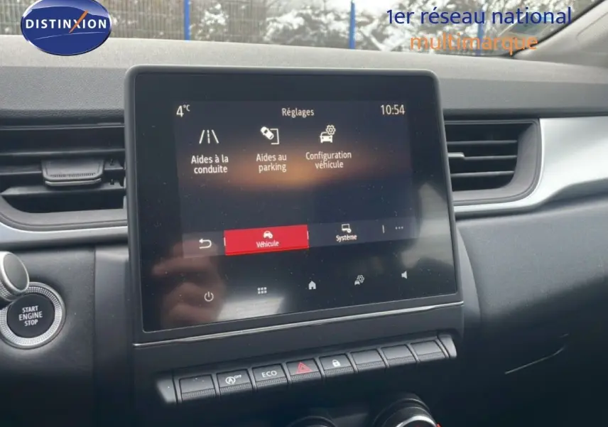Vue intérieure centrée sur l'écran tactile du tableau de bord du Renault Captur gris Cassiopée, avec commandes et bouton Start visible.