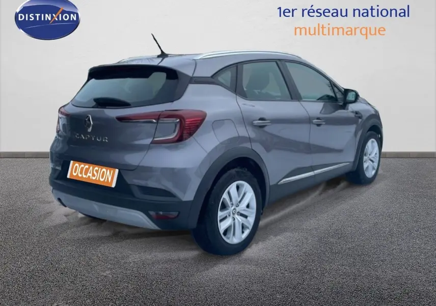 Vue 3/4 arrière droite d’un Renault Captur gris Cassiopée métal avec jantes blanches et badge arrière visible.