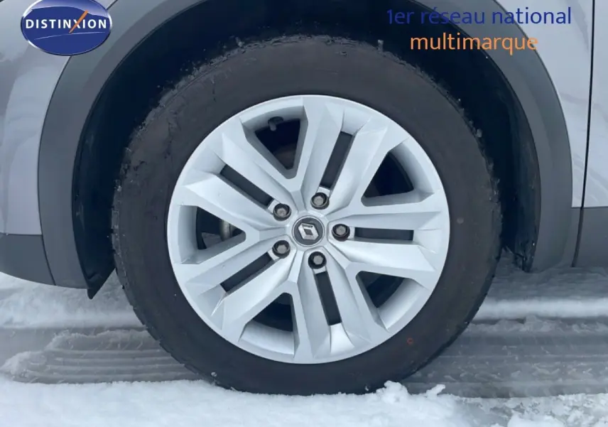 Gros plan sur la roue avant gauche du Renault Captur gris Cassiopée métal, avec jante alliage et neige au sol.