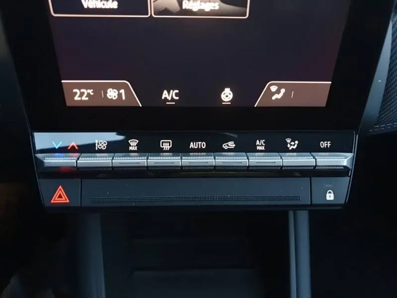 Gros plan sur la console centrale tactile du Renault Captur 2025 bleu Iron, avec commandes climatisation et bouton hazard rouge.