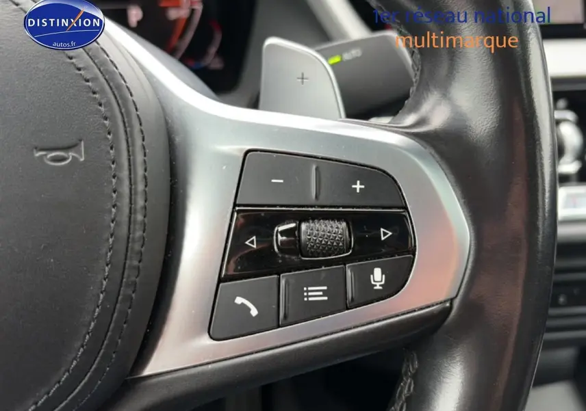Gros plan sur les commandes multifonctions en métal brossé du volant cuir noir d’une BMW Série 2 Gran Coupe F44.