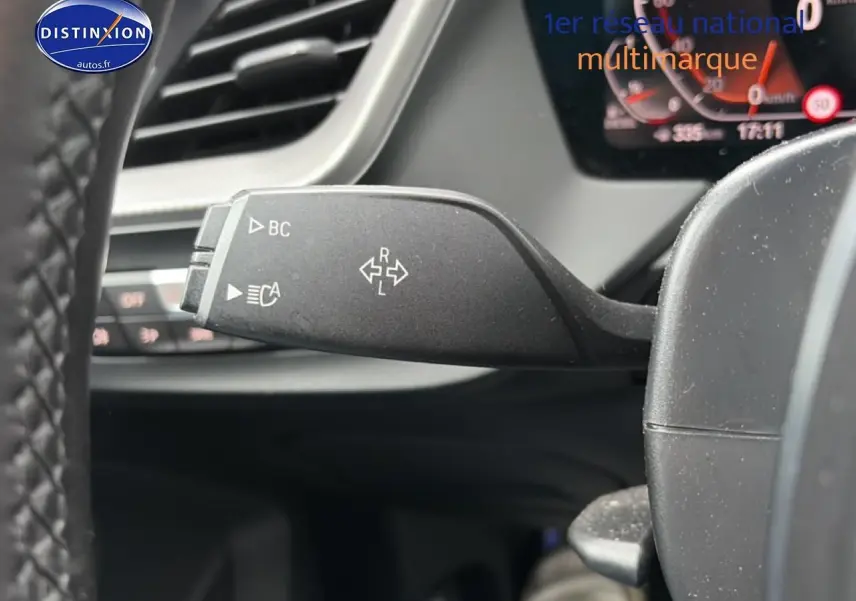 Gros plan sur la commande de clignotant à gauche du volant dans l’habitacle d’une BMW Série 2 Gran Coupe gris 2021.