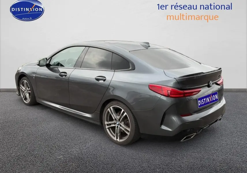 BMW Série 2 Gran Coupé gris vue 3/4 arrière droit, jantes alu et double sortie d’échappement chromée.
