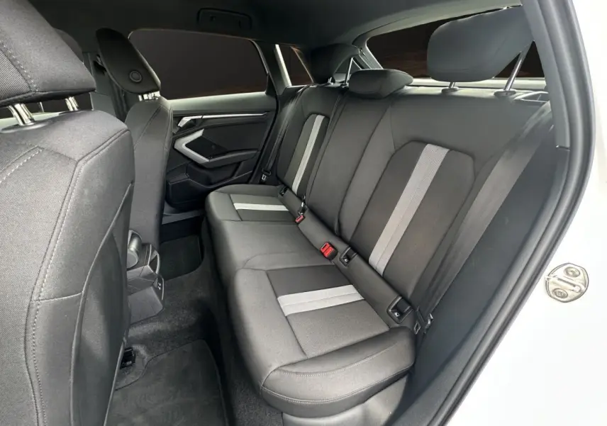 Vue intérieure côté droit des sièges arrière en tissu gris avec bandes claires de l'Audi A3 blanche 2024.