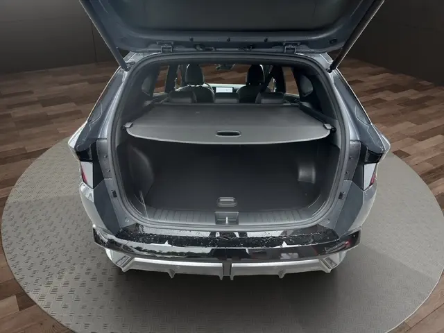 Vue arrière du Hyundai Tucson gris foncé 2026 avec hayon motorisé ouvert, montrant le coffre spacieux et la tablette de rangement.