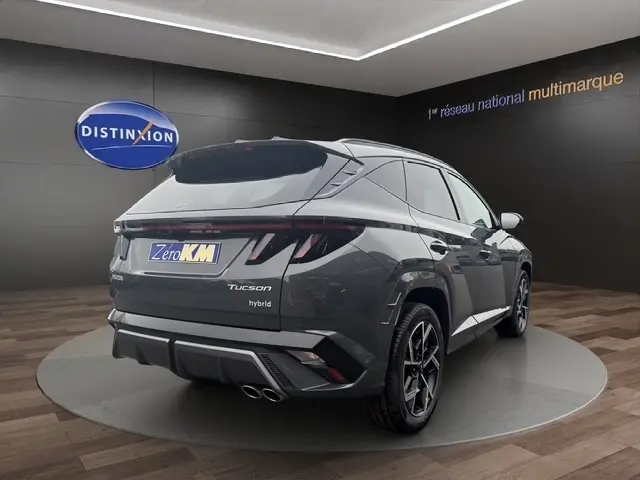 Vue 3/4 arrière droite d'un Hyundai Tucson gris foncé avec hayon motorisé et double sortie d'échappement chromée.