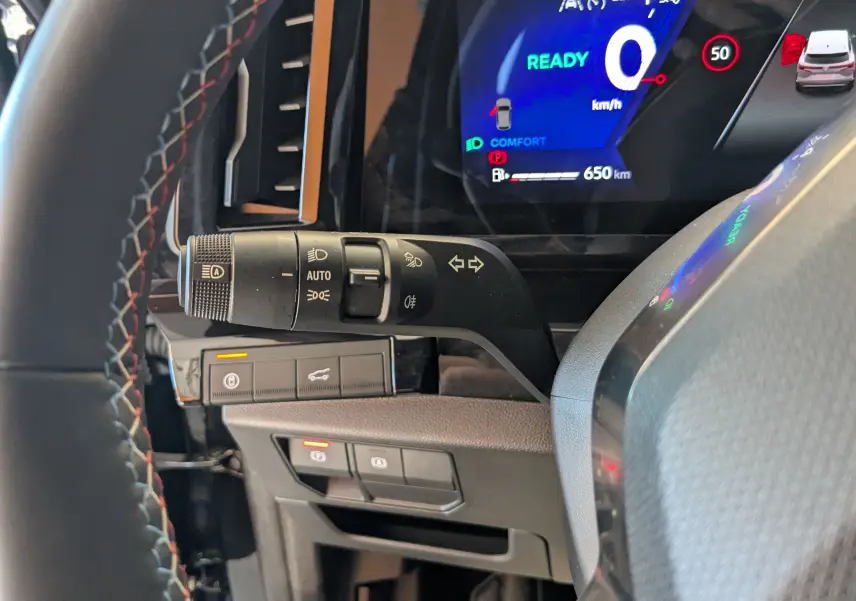 Gros plan sur la commande des feux et clignotants à gauche du volant dans l’habitacle noir du Renault Espace VI hybride.