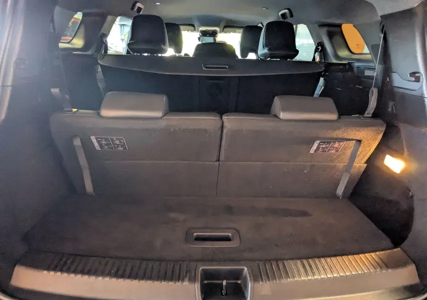 Vue intérieure arrière du coffre du Renault Espace VI noir étoile avec sièges rabattus et éclairage latéral allumé.