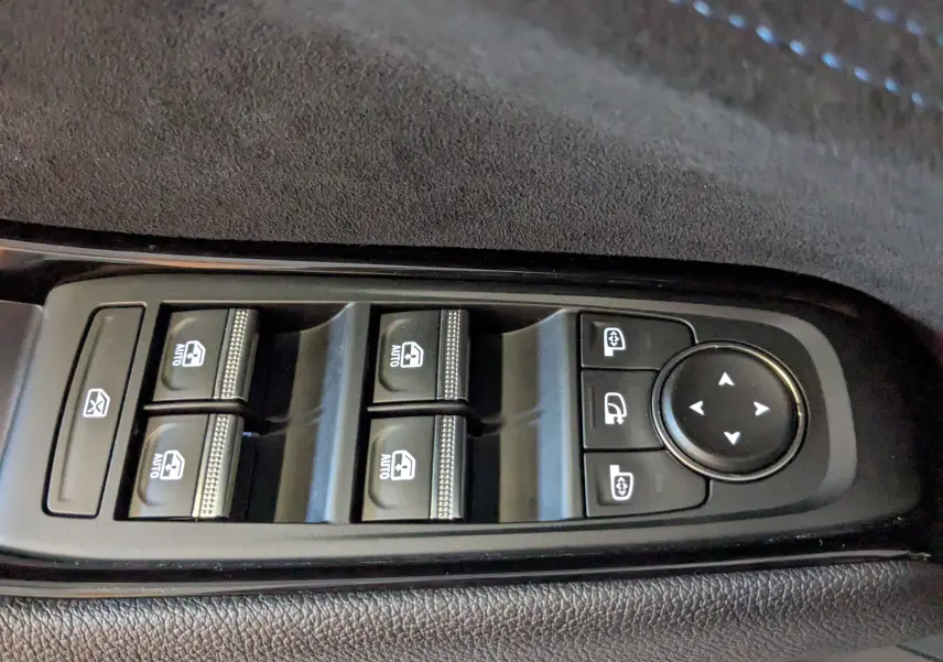 Gros plan sur les commandes des vitres électriques et rétroviseurs du côté gauche intérieur du Renault Espace VI noir étoile.