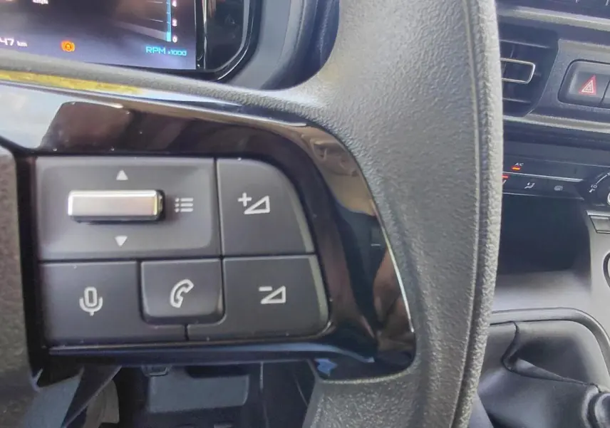 Gros plan sur les commandes du volant multifonctions d’un Citroën Berlingo blanc 2025, version essence manuelle.