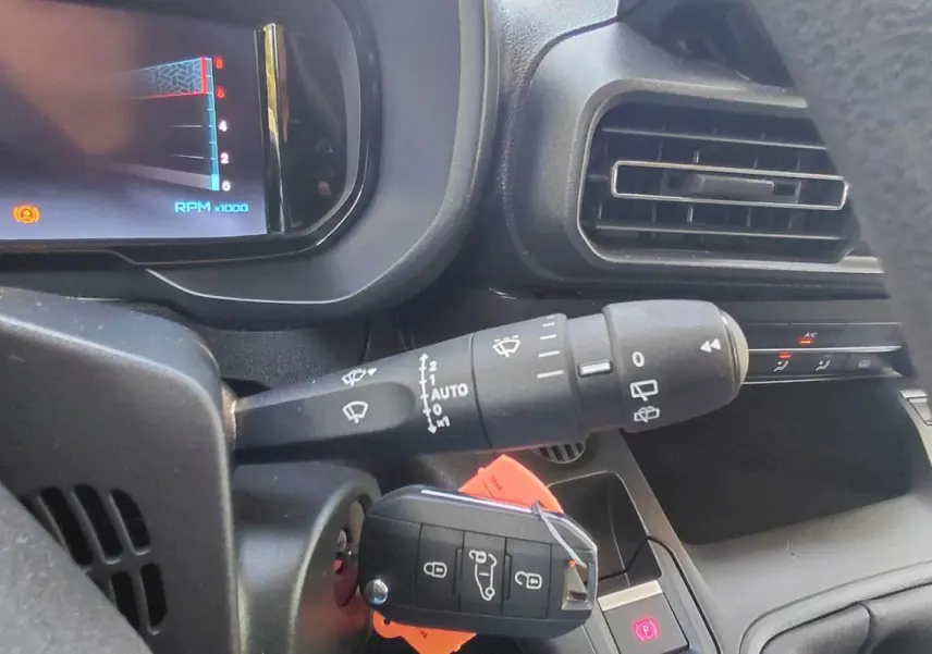 Gros plan sur le tableau de bord et la clé de contact du Citroën Berlingo 2025, avec commandes de phares et ventilation visibles.