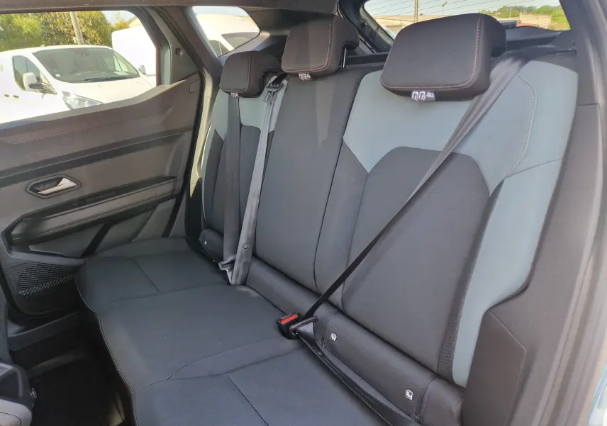 Vue latérale gauche de la banquette arrière du Dacia Duster 2026, sièges bi-ton gris et noir avec ceinture de sécurité.