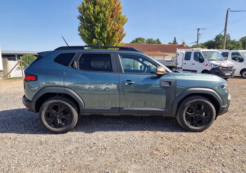 Vue de profil côté gauche du Dacia Duster 1.8 Hybrid 155 Extreme vert cèdre avec jantes noires et rétroviseurs bronze.