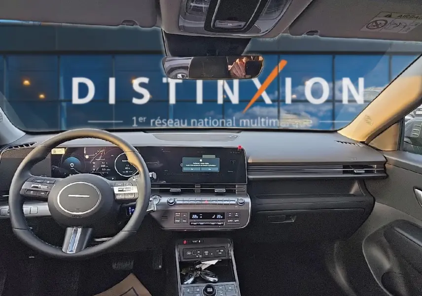 Vue intérieure avant du Hyundai Kona 2025 gris ecotronic, tableau de bord numérique et volant multifonction cuir.