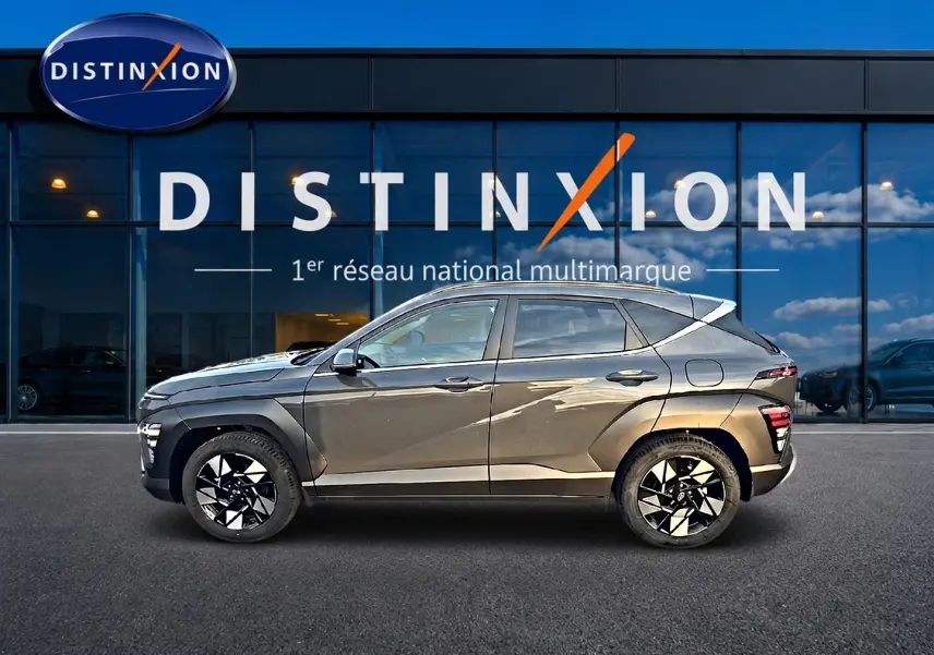 Vue de profil côté gauche d'une Hyundai Kona gris ecotronic avec jantes alliage noires et blanches, devant une vitrine Distinxion.