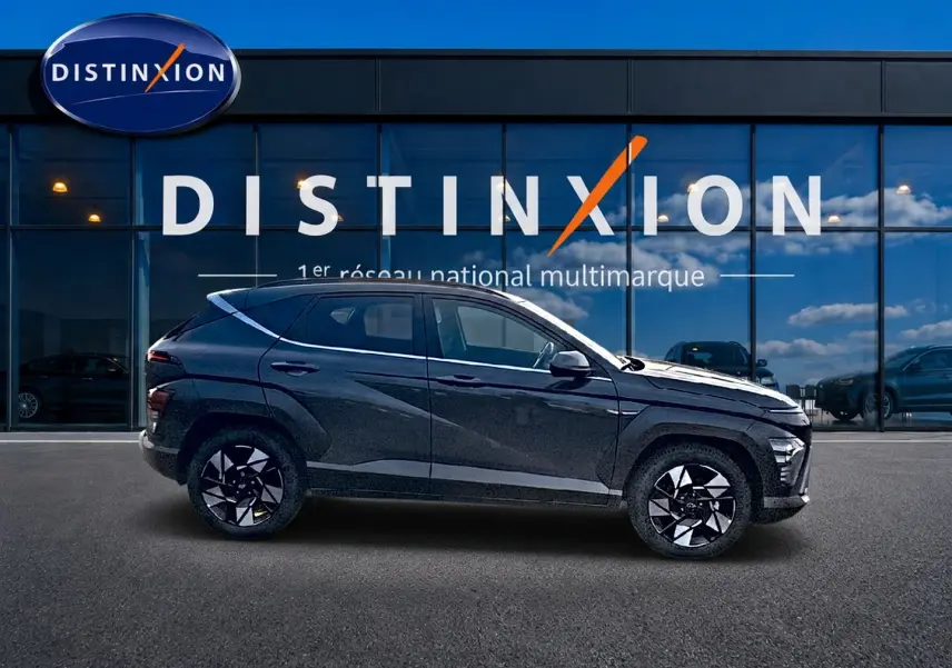 Profil droit du Hyundai Kona 2025 gris ecotronic avec jantes alliage noires et design moderne devant une vitrine Distinxion.