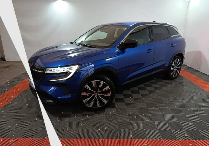 Renault Austral Techno bleu en 3/4 avant droit, avec jantes alliage et phares LED allumés dans un studio.