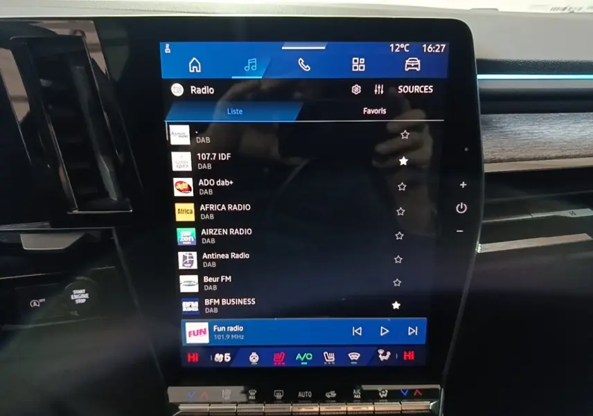 Gros plan sur l’écran tactile central du tableau de bord du Renault Austral bleu, affichant les stations radio numériques.