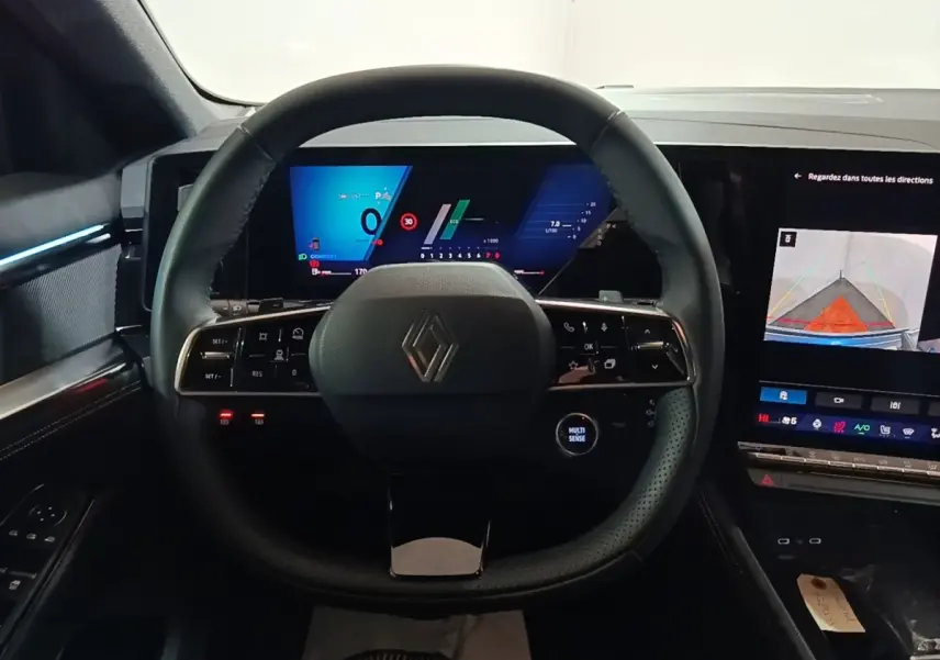 Vue intérieure centrée sur le volant cuir multifonctions et les écrans digitaux du tableau de bord du Renault Austral 2024.