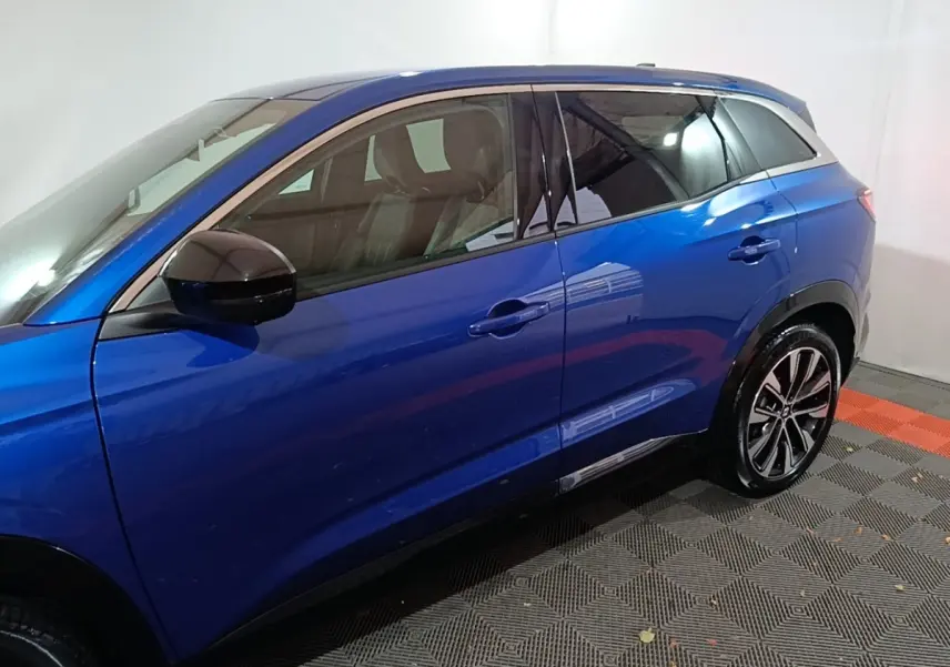 Vue latérale gauche d'un Renault Austral bleu 2024 avec rétroviseurs noirs et jantes alliage bicolores.