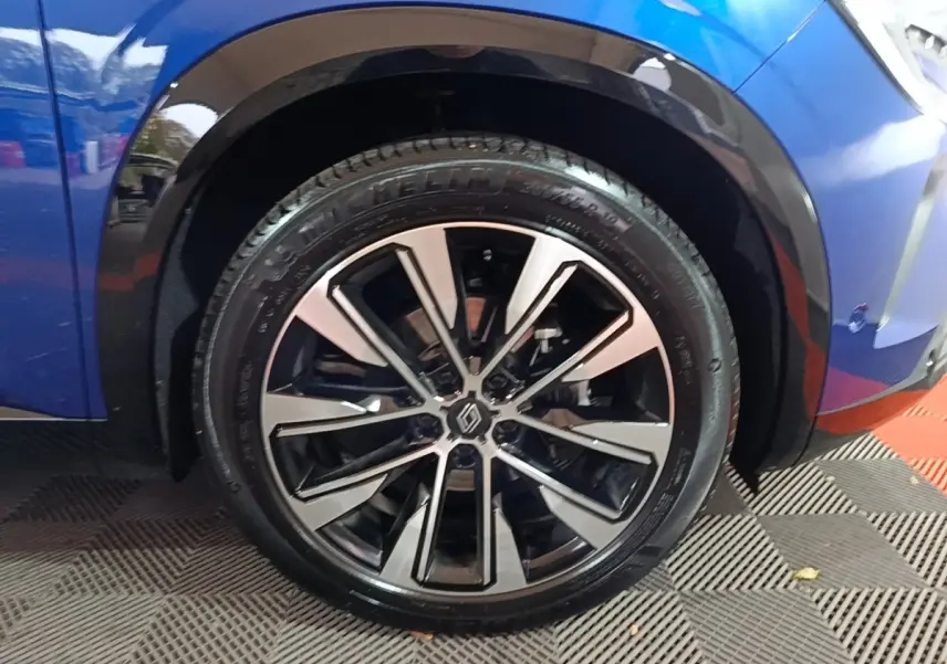 Gros plan sur la roue avant droite d’un Renault Austral bleu 2024 avec jante alliage bicolore moderne.