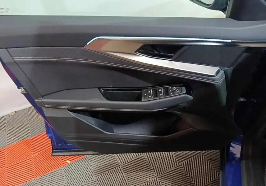 Vue rapprochée de la porte avant gauche bleu Renault Austral 2024 avec commandes de vitres et éclairage d'ambiance.
