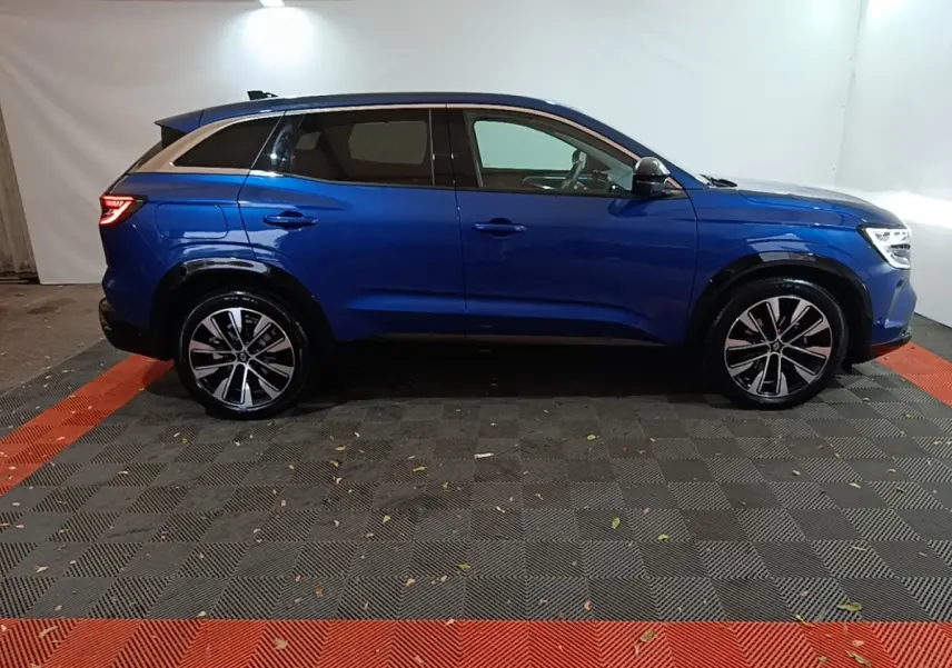 Profil droit du Renault Austral bleu 2024 avec jantes alliage et toit noir contrasté dans un studio.