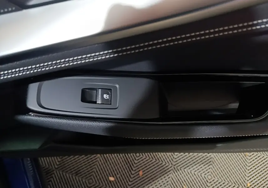 Détail de la commande de verrouillage sur la porte côté gauche du Renault Austral bleu, avec surpiqûres blanches visibles.