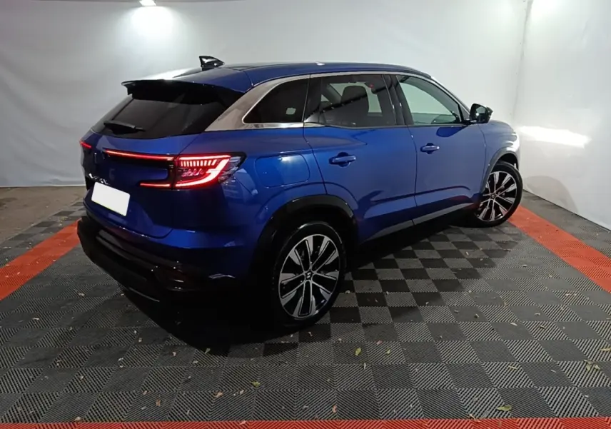 Renault Austral bleu en vue 3/4 arrière droit, feux LED allumés et jantes alliage distinctives.