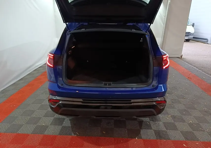 Vue arrière d'un Renault Austral bleu 2024 avec coffre ouvert et feux arrière allumés dans un garage.