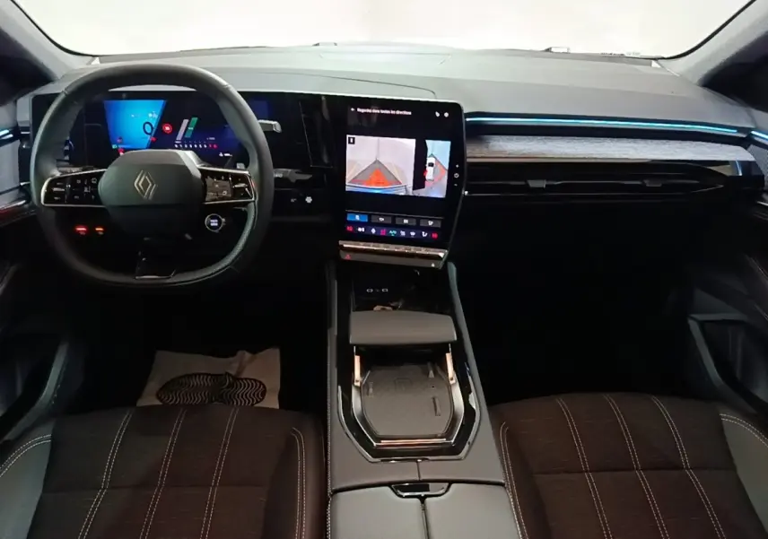 Intérieur Renault Austral 2024 vu de face, volant cuir multifonctions, écran tactile central vertical et éclairage d'ambiance bleu.