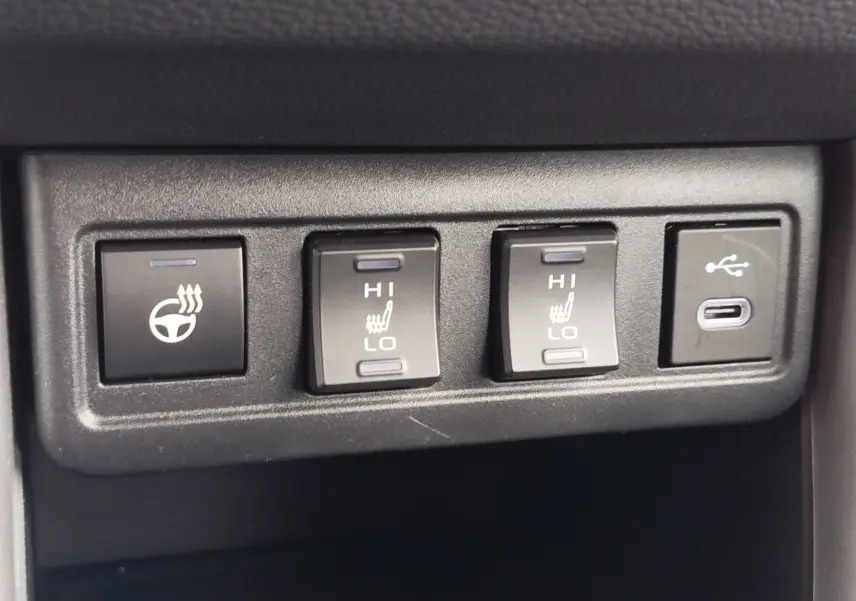Gros plan sur les commandes de chauffage de volant et sièges avec port USB dans le Toyota Corolla Cross gris acier 2025.