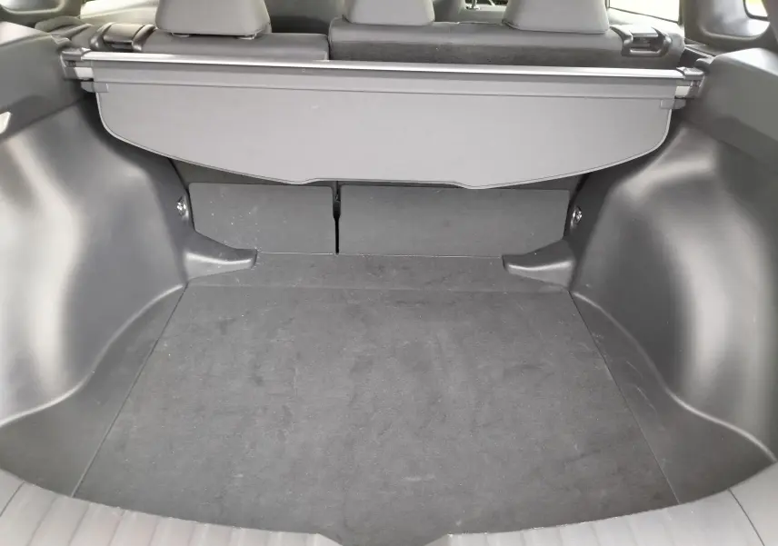 Coffre spacieux du Toyota Corolla Cross gris acier 2025, vue intérieure arrière avec cache-bagages déployé.