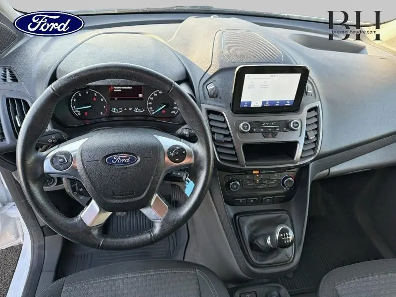 Vue intérieure centrée sur le volant multifonction et la console centrale du Ford Transit Connect blanc glacier 2022.