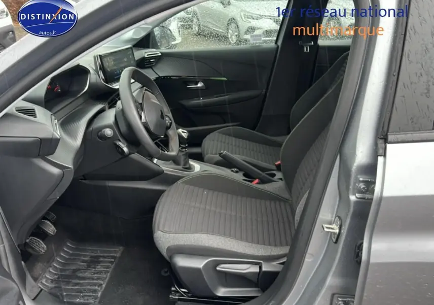 Vue intérieure côté conducteur de la Peugeot 208 1.2 PureTech 100 Active gris Artense avec sièges tissu noir/gris.