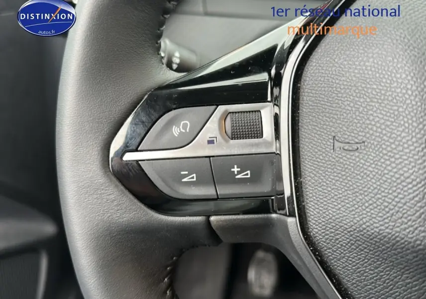 Gros plan sur les commandes audio au volant noir d'une Peugeot 208 1.2 PureTech 100 Active 2024, intérieur gris.