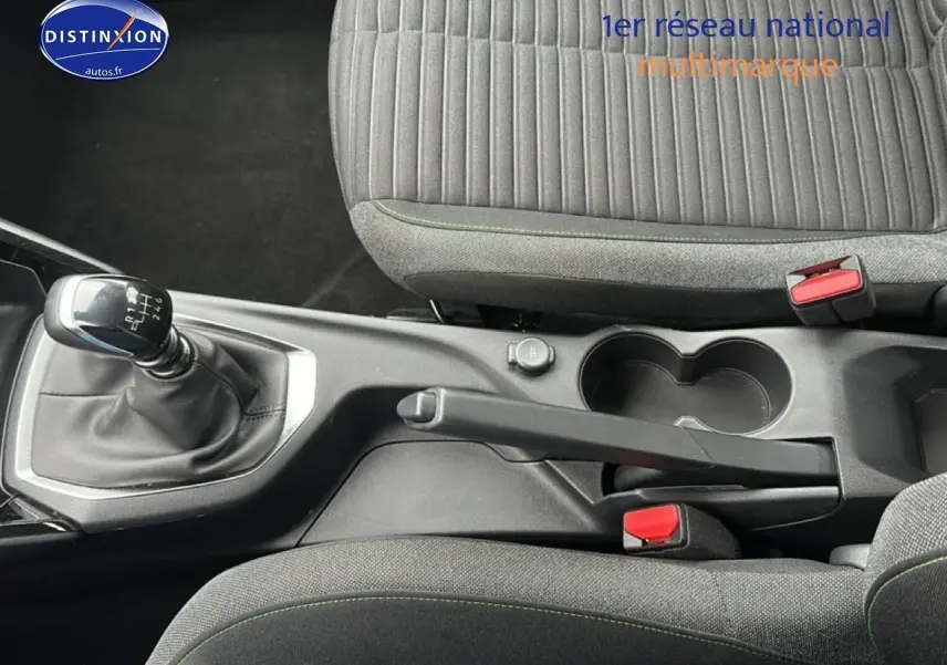 Vue intérieure centrée sur la console centrale d'une Peugeot 208 gris artense avec levier de vitesse manuel et sièges tissu noir/gris.
