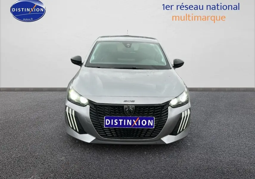 Vue frontale d'une Peugeot 208 1.2 PureTech 100 Active gris Artense avec feux diurnes LED allumés.
