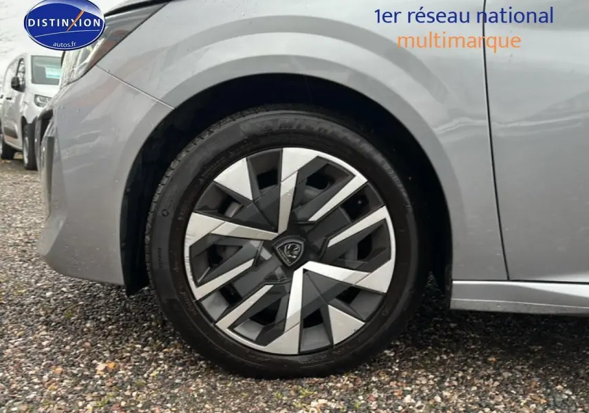 Gros plan sur la roue avant gauche d'une Peugeot 208 gris artense, mettant en valeur la jante au design géométrique.