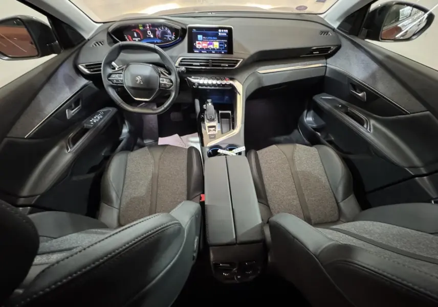 Intérieur noir et gris du Peugeot 3008 PureTech 130, vue avant centrée sur le tableau de bord et le volant compact.
