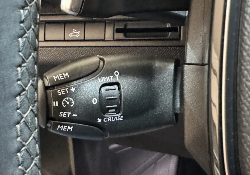 Gros plan sur la commande de régulateur de vitesse noire dans l’habitacle du Peugeot 3008 PureTech 130 orange.