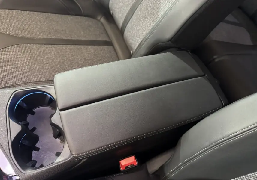 Gros plan sur l'accoudoir central noir et porte-gobelets du Peugeot 3008 PureTech 130 essence, intérieur tissu gris.