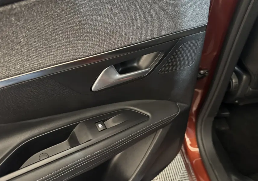 Gros plan sur la porte arrière gauche noire avec poignée argentée et partie extérieure orange du Peugeot 3008 2020.