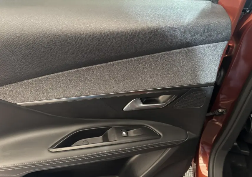 Vue rapprochée de la porte arrière gauche orange du Peugeot 3008 2020, avec garniture noire et tissu gris.