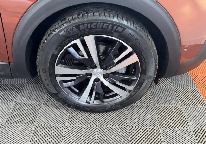 Gros plan sur la roue avant droite du Peugeot 3008 orange, avec jante alliage bicolore et pneu Michelin.