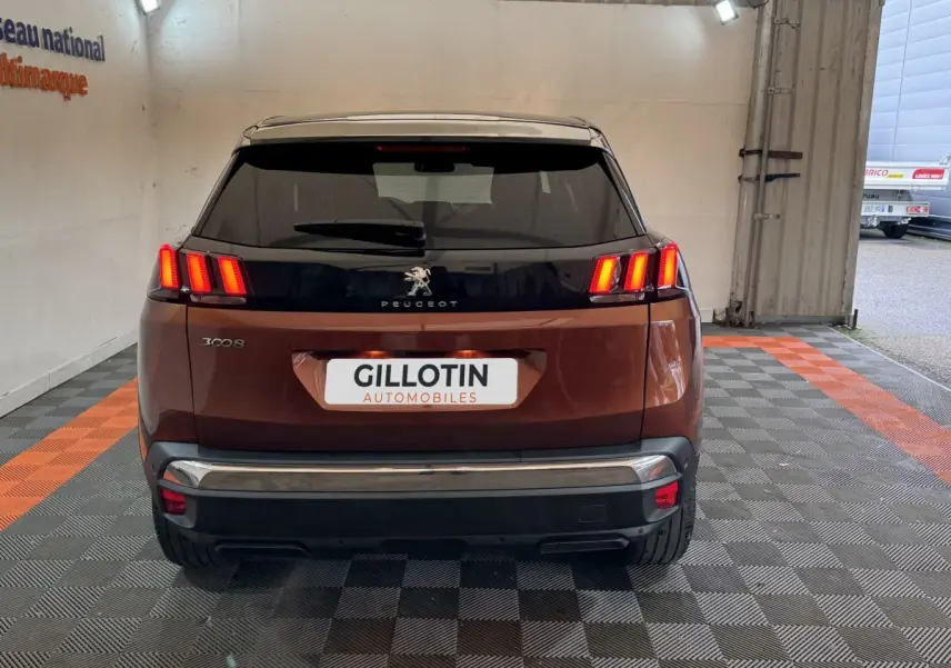 Vue arrière du Peugeot 3008 orange avec feux LED allumés, dans un espace couvert au sol damier noir et orange.